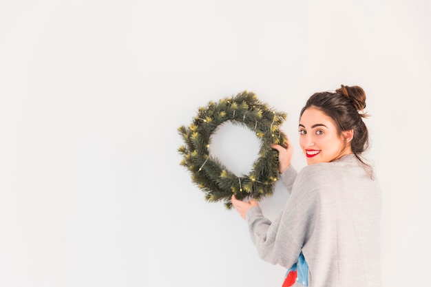 Woman in grey hanging Christmas wreath