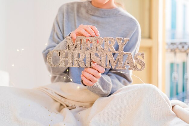 Woman in grey holding glitter Merry Christmas inscription