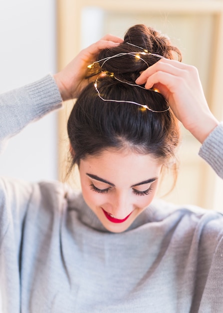 Woman in grey holding hands on topknot with garland