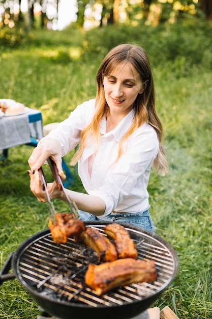 自然の中で肉を焼く女