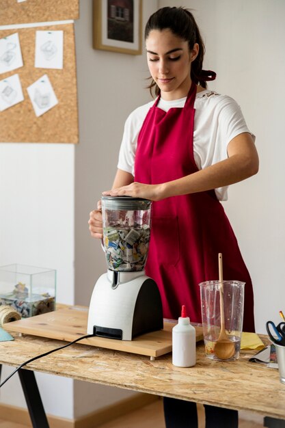 Woman grinding pieces of paper in mixer grinder