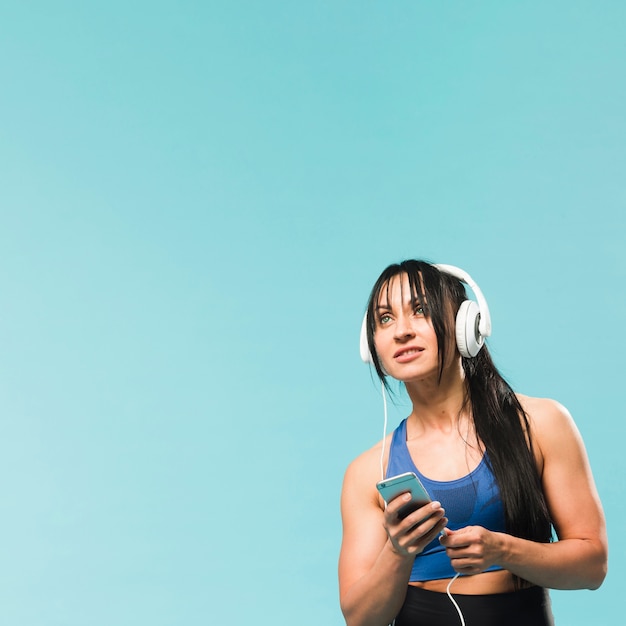 Foto gratuita donna in attrezzatura della palestra che ascolta la musica in cuffie