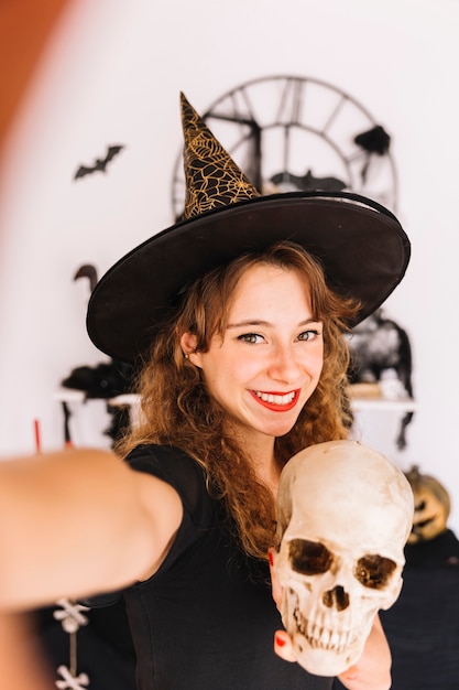 Free photo woman in halloween costume with pointy hat with skull