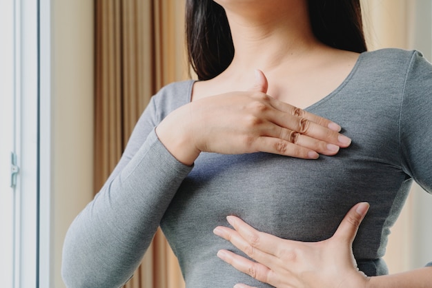 유방암의 징후에 대한 그녀의 가슴에 덩어리를 확인하는 여자 손