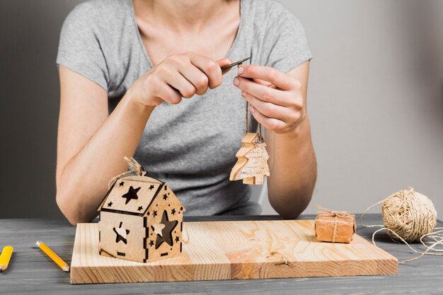 Woman hand cutting string of handmade wooden tree