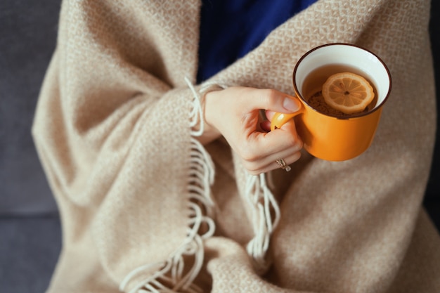 Woman hand holding cup of tea with lemon