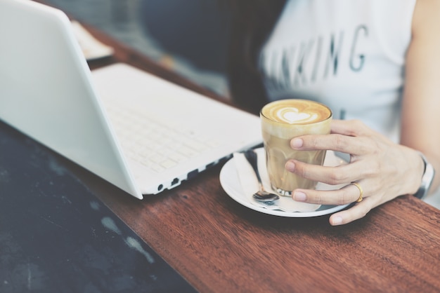 Foto gratuita mano della donna che tiene un vetro con la tazza di caffè