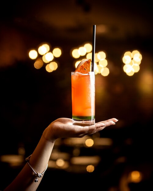 Woman hand holding grapefruit cocktail with black straw