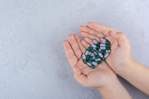 Woman hand holding medical capsules on marble.