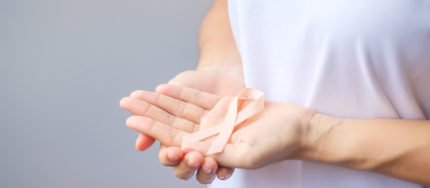 Woman hand holding peach ribbon for september uterine cancer awareness month. healthcare and world cancer day concept