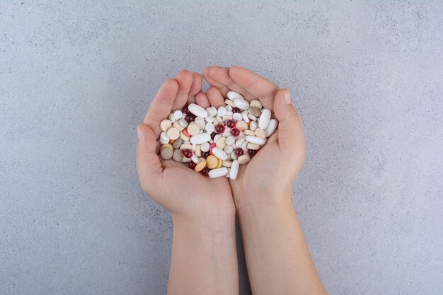 Woman hand holding pile of pills on marble. High quality photo