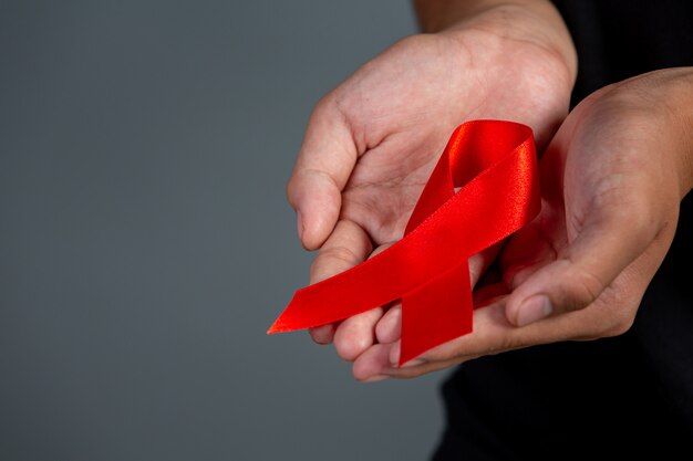 Woman hand holding red ribbon HIV awareness concept World AIDS Day and World Sexual Health Day.