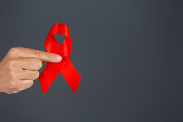 여자가 손을 잡고 빨간 리본 HIV 인식 개념 세계 에이즈의 날 및 세계 성 건강의 날.