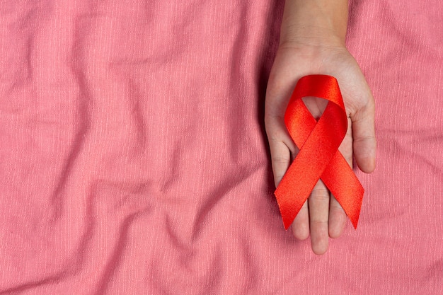 여자가 손을 잡고 빨간 리본 HIV 인식 개념 세계 에이즈의 날 및 세계 성 건강의 날.