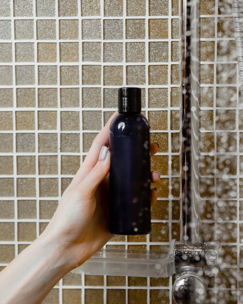 Женщина рука гель для душа в бутылке военно-морского флота в ванной комнате
