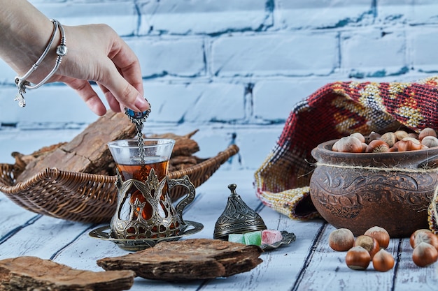 Woman hand holding a spoon of tea and various sweets on blue wooden table