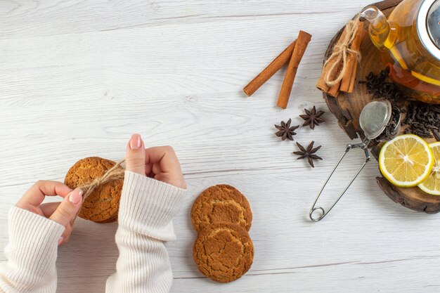 Woman hand holding stacked cookies black tea with lemon