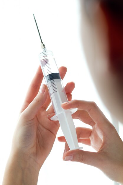 Woman hand holding syringe. Isolated on a white.