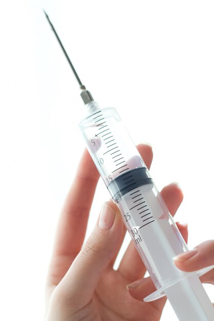 Woman hand holding syringe. Isolated on a white.