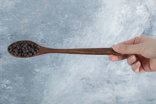 Женщина рука деревянную ложку шоколадной стружки.