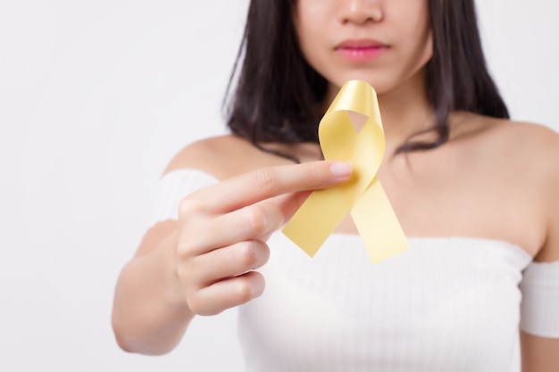 Woman hand holding yellow ribbon bow, suicide, military forces, fire service, endometriosis awareness symbol, yellow ribbon for medical, charity fund raising concept