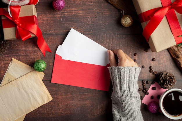 Woman hand is putting greeting card into envelope