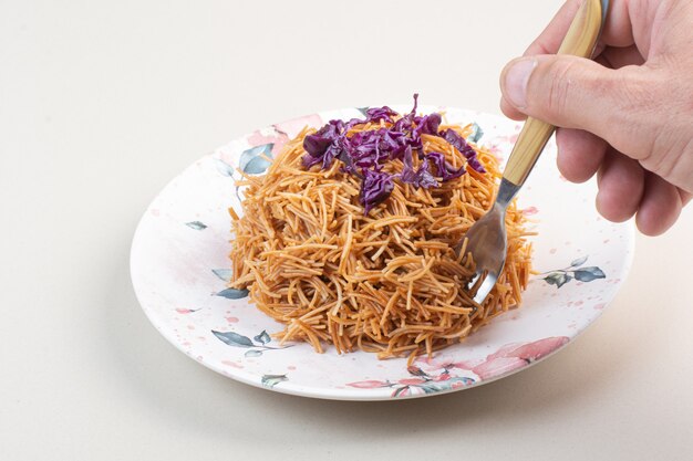 Женщина рука берет спагетти из тарелки с вилкой
