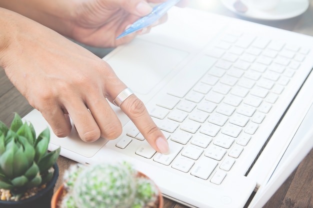 Free photo woman hand using laptop computer and holding credit card, online shopping