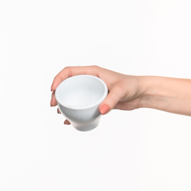 白い背景の上にカップを持つ女性の手