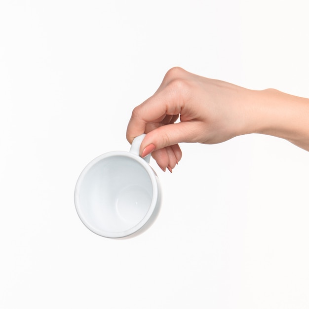 Mano della donna con la tazza su bianco