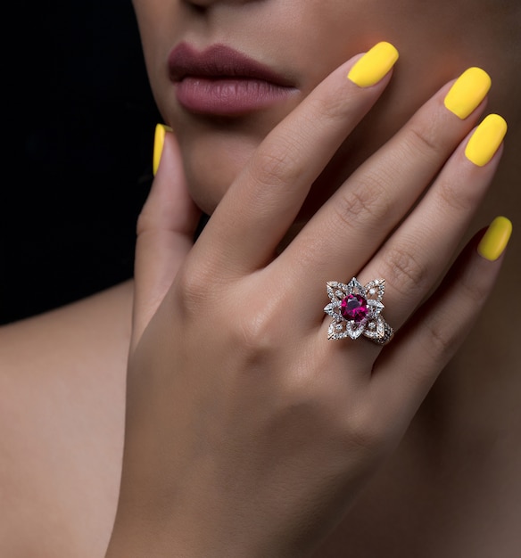 Free photo woman hand with flower-shaped diamond ring with white and burgundy stone