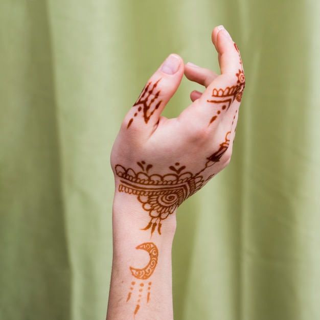 Woman hand with mehndi paints near textile