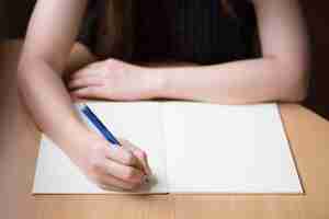 Foto gratuita scrittura della mano della donna su un libro in bianco