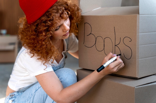 Женщина обрабатывает вещи в картонных коробках для переезда в новый дом