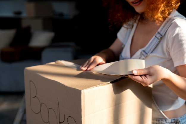 Woman handling belongings in cardboard boxes for moving in new house