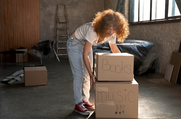 Woman handling belongings in cardboard boxes for moving in new house