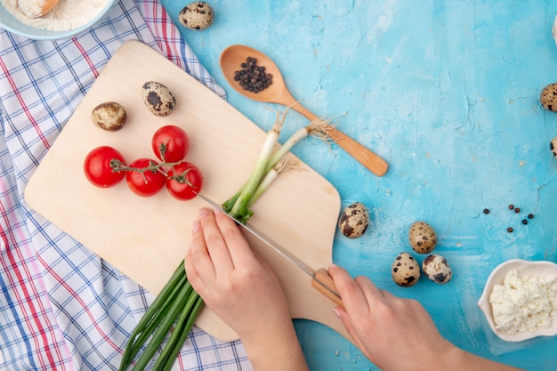 женщина руки резки лук-шалот и другие продукты и овощи на синем столе