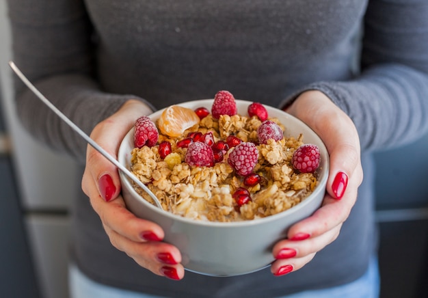 Free photo woman hands holding cereal and fruit bowl