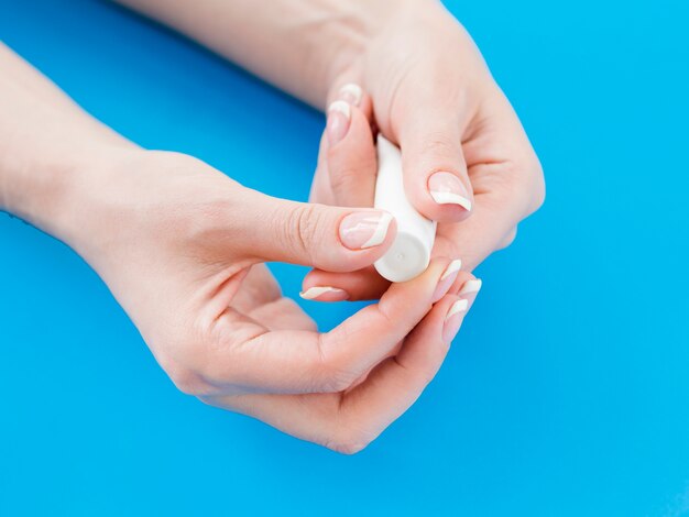 Woman hands holding cream tube on blue background