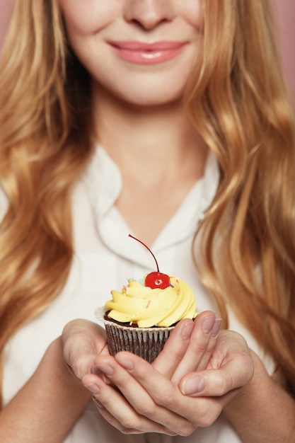 Free photo woman hands holding a delicious yummy cupcake