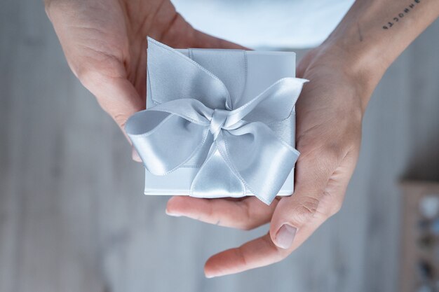 Woman hands holding Gift box with white bow, close-up