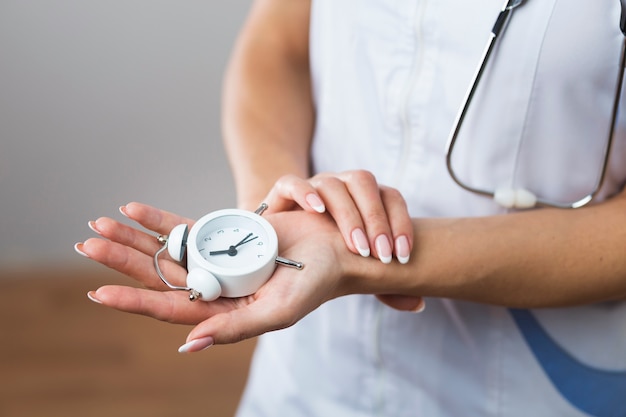 Free photo woman hands holding a little clock