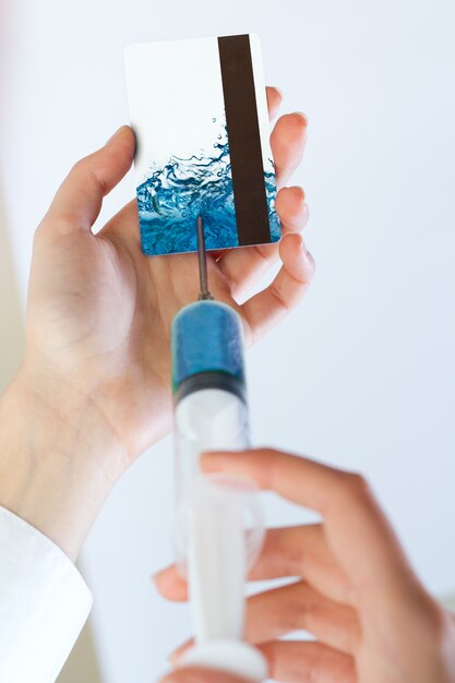 Woman hands injecting liquid into a credit card with a syringe. Cash injection concept