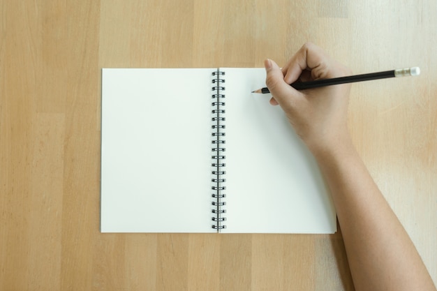 Woman hands writing on book in office. Business woman working on desk of wood. Business woman working with laptop and office supplies on top view. Copy space. Vintage effect style pictures.