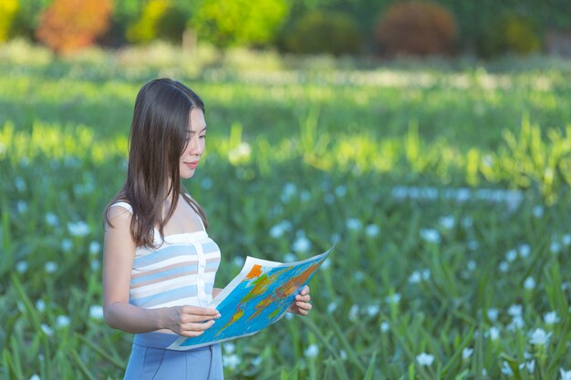 woman happily holding a tourist map in the flower garden