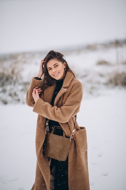 Donna felice in cappotto in inverno fuori nel parco