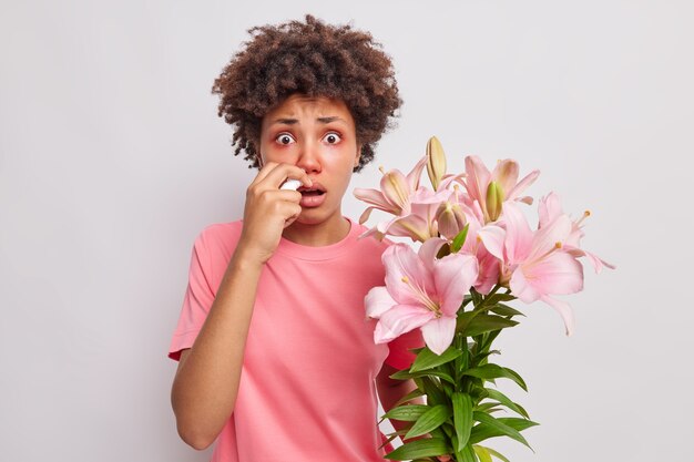 woman has allergy to lily suffers from runny nose and other unpleasant symptoms uses nasal drops sneezes constantly poses indoor on white 