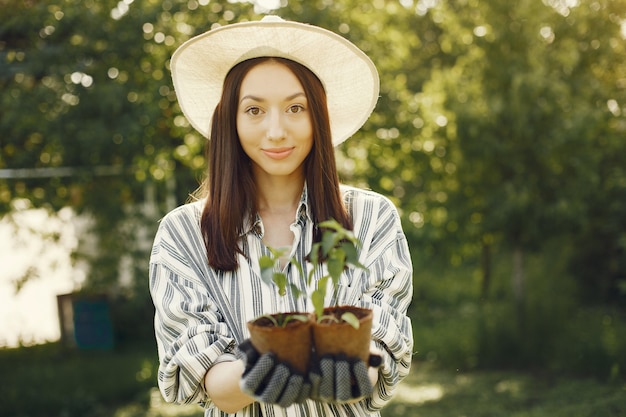 La donna in un cappello che tiene i vasi da fiori