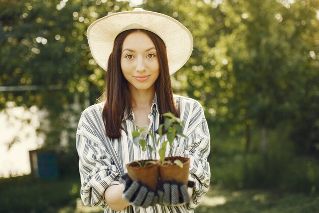 Woman in a hat holding flowerpots