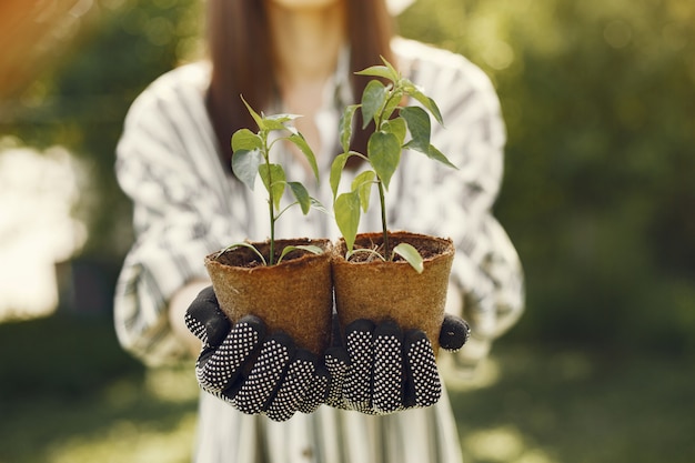 Foto gratuita la donna in un cappello che tiene i vasi da fiori